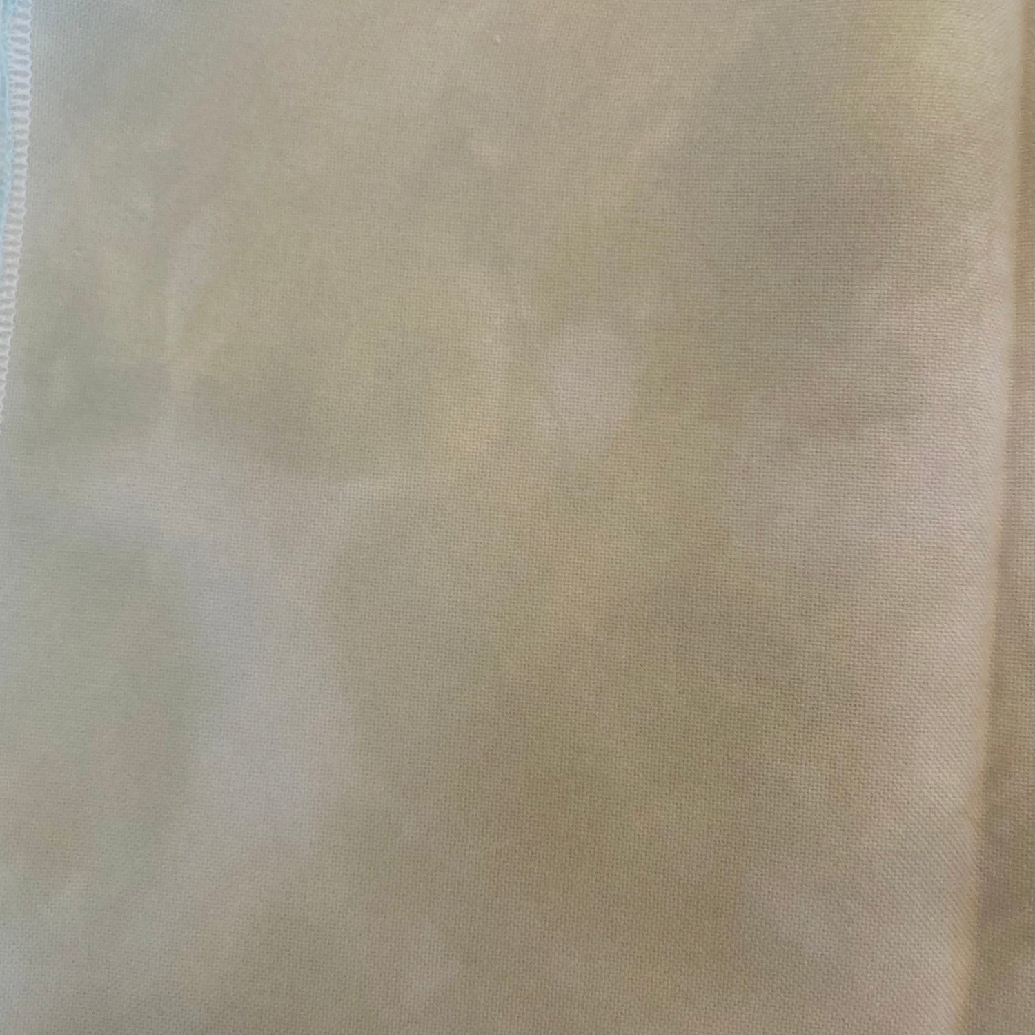 32 count Cobblestone linen from Atomic Ranch Fabrics. A close-up image of a hand dyed, variegated, light cream colored 32 count linen fabric.
