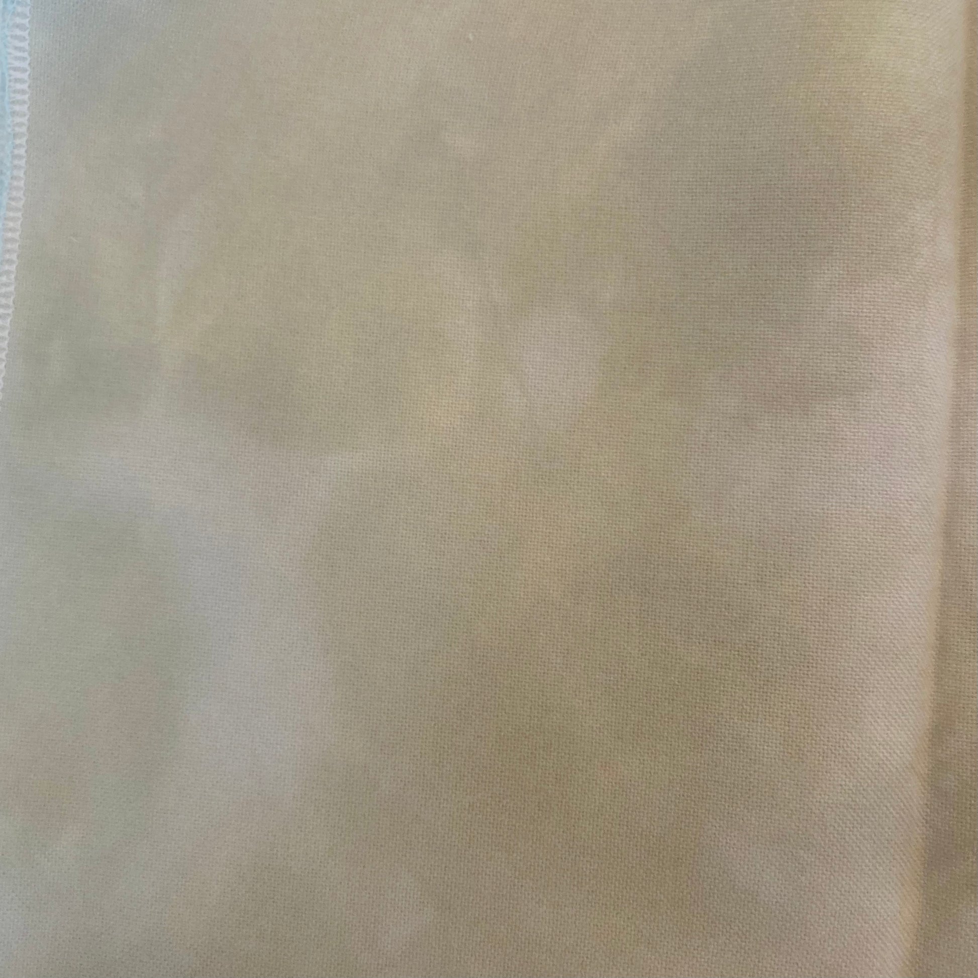 32 count Cobblestone linen from Atomic Ranch Fabrics. A close-up image of a hand dyed, variegated, light cream colored 32 count linen fabric.